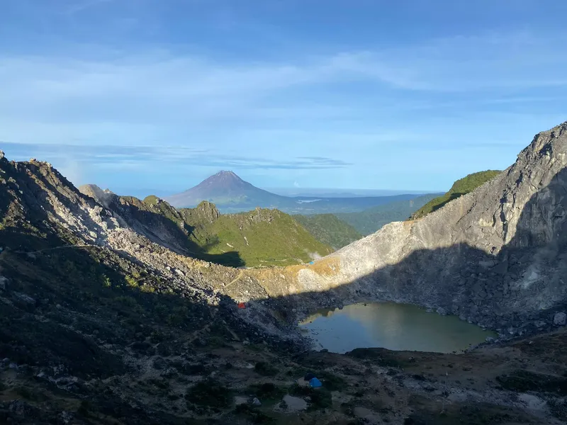 Mount Sibayak's crater lake with camp tents and Mount Sinabung on the horizon