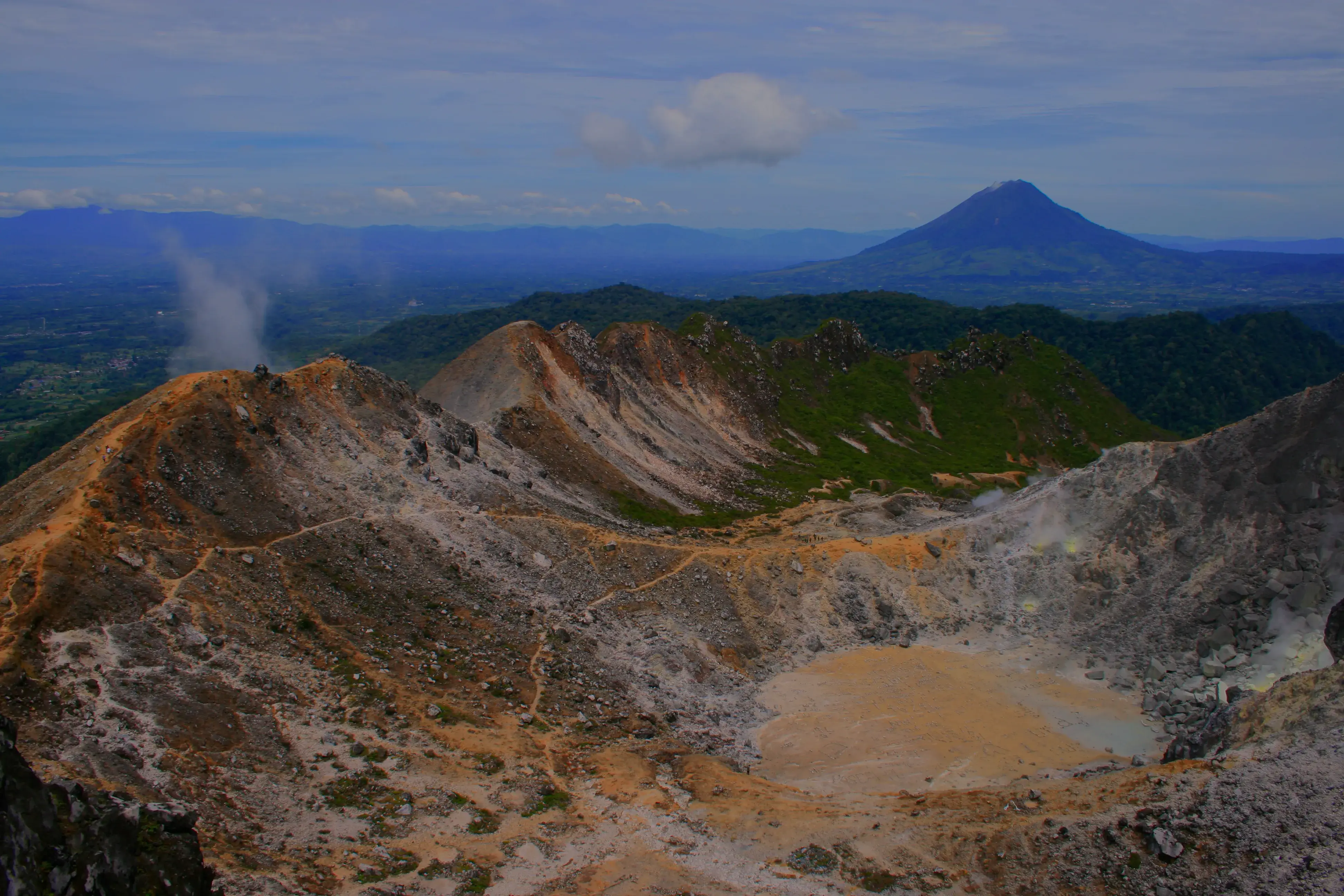 Cinematic wide shot of Mount Sibayak volcano crater at sunrise with thick atmospheric mist and soft teal morning light