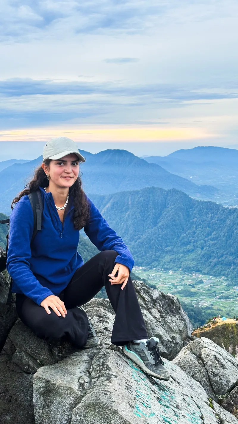 A guest resting on the summit rocks above the Karo Highlands at dusk