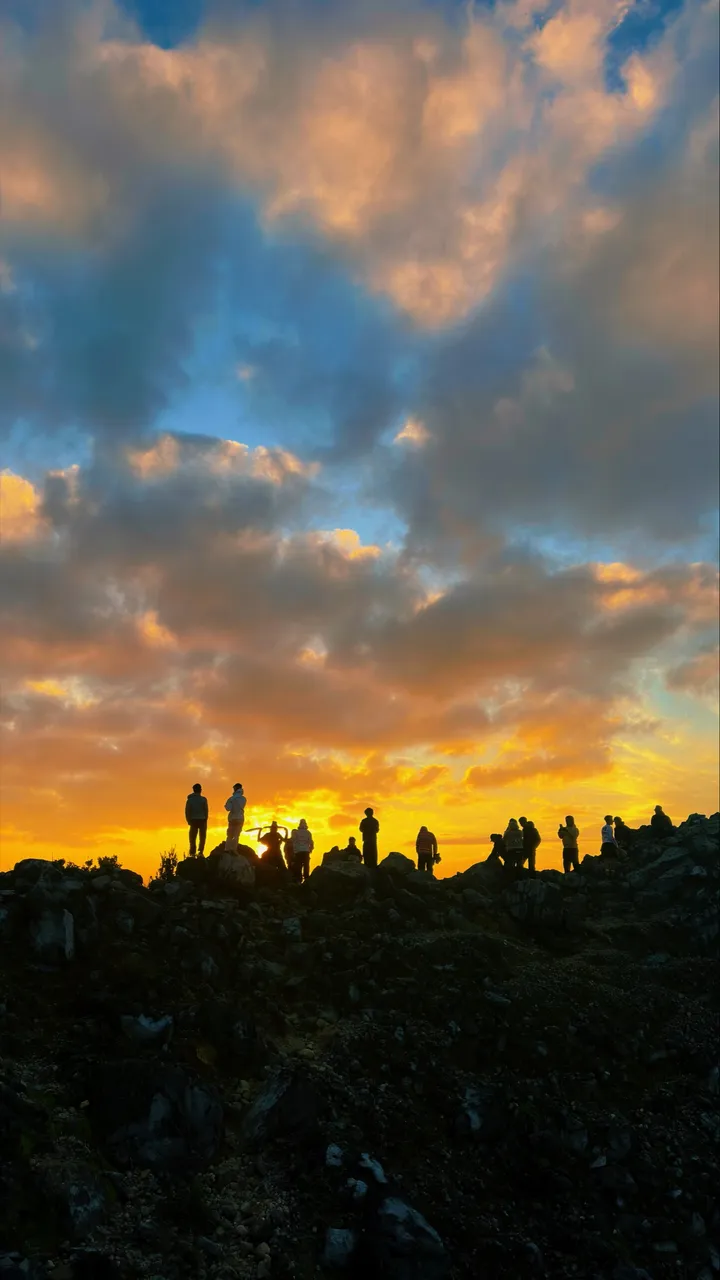 Trekkers silhouetted at the Mount Sibayak summit at sunrise