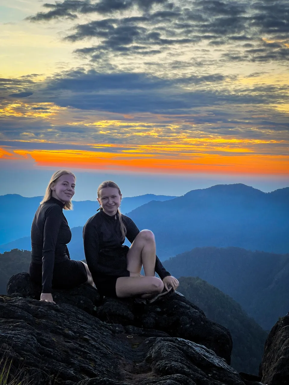 Two hikers with a guide at sunrise on the Mount Sibayak ridge